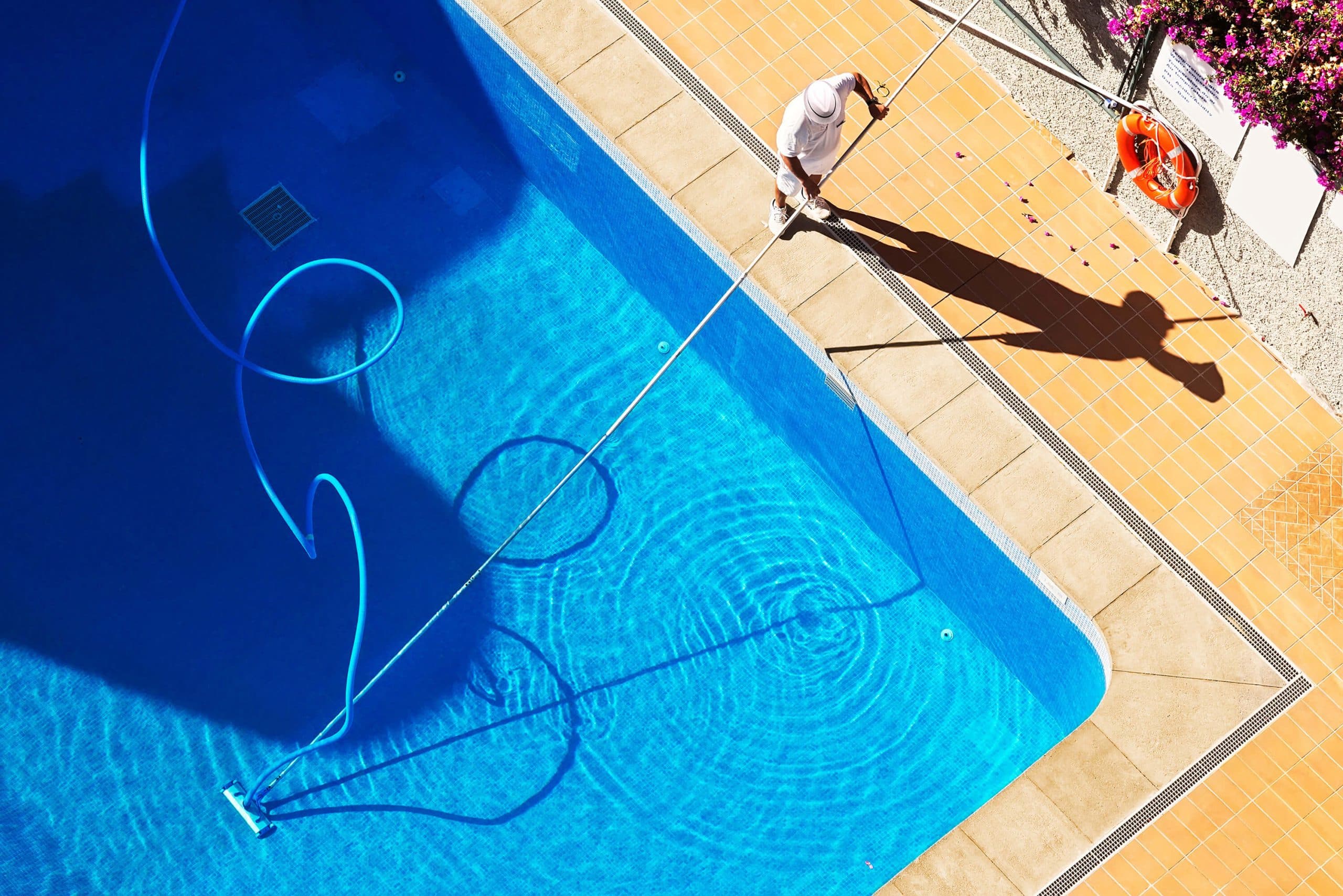 Pool service technician cleaning a pool — aerial view