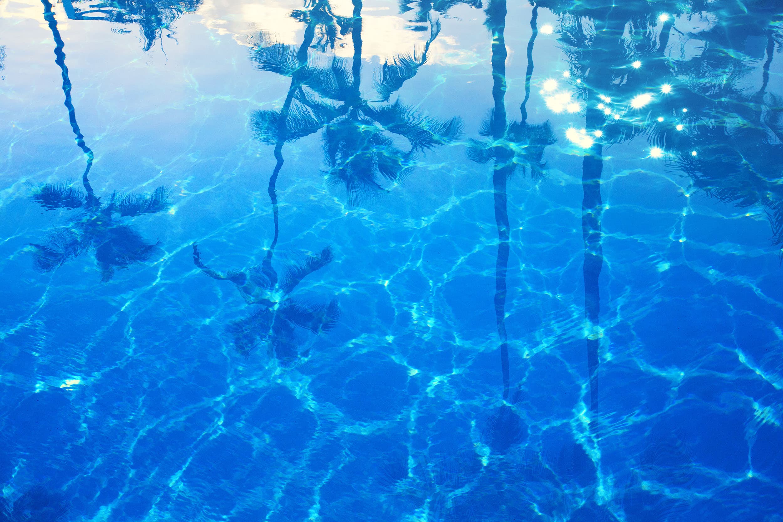 Crystal clear pool water with palm tree reflections in Southern California